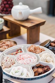 an assortment of desserts are arranged in bowls on a table with teapots