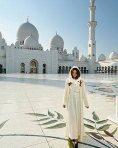 a woman standing in front of a white building with many arches and domes on it