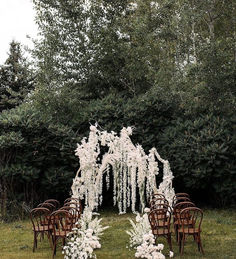 an outdoor ceremony setup with white flowers and chairs