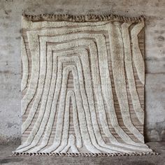 a large rug with fringes on the floor in front of a chair and wall