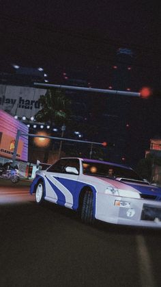 a white and blue car driving down a street at night