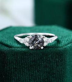 an engagement ring with two diamonds on it sitting on top of a green velvet box