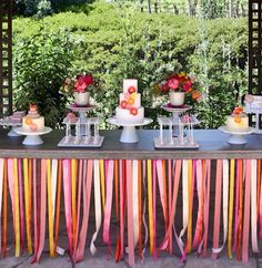 a table topped with lots of cakes and desserts on top of tables covered in ribbons