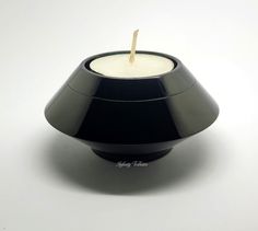 a black candle holder with a wooden stick sticking out of it's center, on a white background