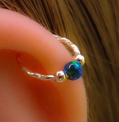 a close up view of an ear with a blue bead on the middle part