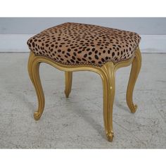 a leopard print upholstered foot stool with gold trimmings and wood legs