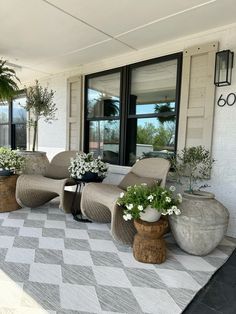 an outdoor patio with chairs and potted plants on the side of the porch area