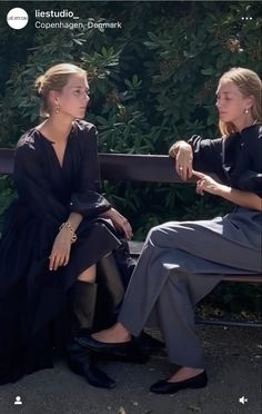 two women are sitting on a bench and one is holding the other's hand