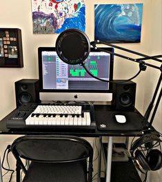 a computer desk with a keyboard, mouse and headphones on it in front of a painting