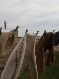 clothes hanging on a line outside in the grass, with one being pulled up to dry