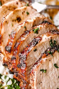 sliced pork chops on a plate with parsley and garlic sprinkled on top