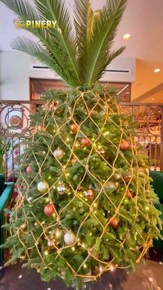 a christmas tree with lights and ornaments on it's top is in the middle of a room