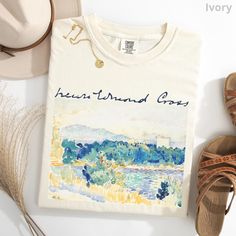 Henri-Edmond Cross' "Mediterranean Landscape with a White House" and a scan of Cross' signature are printed on a garment-dyed Comfort Colors t-shirt, crafted entirely from ring-spun cotton. The fabric is soft-washed adding extra comfort to your clothing collection, while its relaxed fit makes it the perfect option for daily wear. The tee's double-needle stitching ensures exceptional durability, and its seamless design helps maintain its shape. FABRICATION 100% ring-spun cotton SIZING Relaxed, re Cotton Tops With Custom Artwork For Summer, Casual Cotton T-shirt With Artwork, Casual Cotton Tops With Artwork, Casual Cotton Top With Artwork, Casual Summer Tops With Artwork, Casual Crew Neck Tops With Artwork, Graphic Cotton Tee With Artwork, Summer Graphic Tee With Artwork, Summer Crew Neck Tops With Artwork