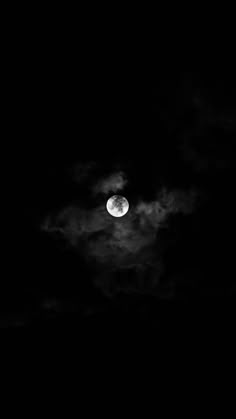 the full moon is seen through clouds in black and white