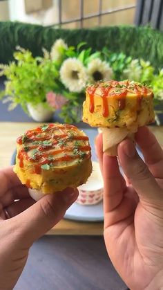 two people holding up small sandwiches with toppings on them