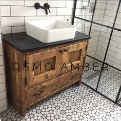 a bathroom with black and white tile flooring and a wooden sink cabinet in the middle