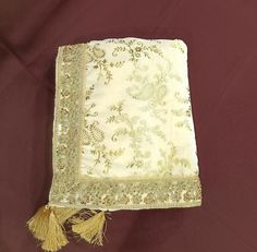 an embroidered square with tassels sits on a red cloth covered tablecloth,