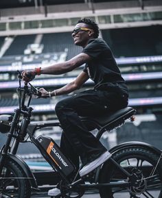 a man riding on the back of a black bike in front of an empty stadium