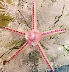 a starfish ornament hanging from a white christmas tree with pink beads and pearls