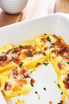 an omelet with bacon and cheese in a white casserole dish on a wooden table