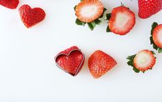 strawberries and heart shaped chocolates on a white surface with one cut in the shape of a heart