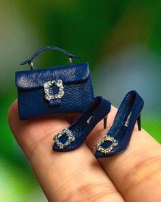 a miniature blue purse and pair of shoes are on display in someone's hand