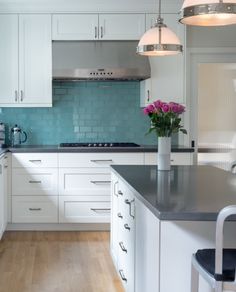 a kitchen with white cabinets and blue backsplash tiles on the wall, along with an island