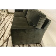 a green couch sitting on top of a rug in front of a white and black area rug