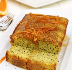 a slice of cake on a plate with orange zest and poppy seeds around it