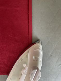 an electric iron sitting on top of a bed next to a red sheet and pillow