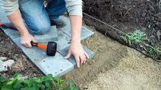 a man kneeling down on top of a cement slab with a tool in his hand