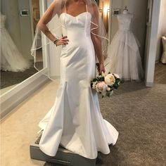 a woman standing in front of a mirror wearing a wedding dress