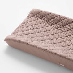 a pink quilted pillow sitting on top of a white surface