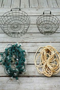 three wire baskets are sitting on a wooden deck with string lights in the middle and one is empty