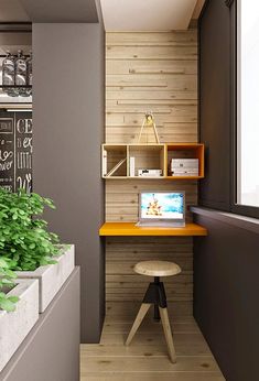 a desk with a laptop on top of it next to a plant in a pot