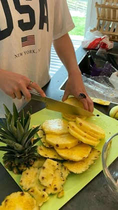 a person cutting up pineapples on a cutting board