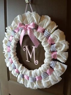 a wreath with the letter m on it is hanging from a door handle and decorated with pink bows