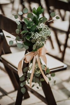 a bouquet of flowers sitting on top of a wooden chair in front of a row of chairs