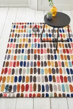 a colorful rug is on the floor in front of a table with a potted plant