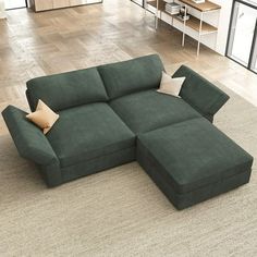 a large green couch sitting on top of a wooden floor next to a white rug