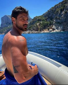 a shirtless man on a boat in the water