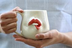 a person holding a coffee mug with a lip painted on it