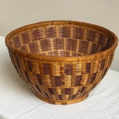 a wicker basket sitting on top of a white cloth covered table with a wooden handle