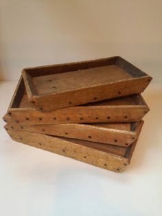 four wooden trays stacked on top of each other with holes in the bottom and sides