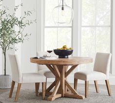 a dining room table with four chairs and a bowl of fruit on the table next to it