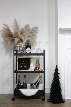 Black Ikea bar cart. Styled next to a cone shaped black feather Christmas tree. Bar cart styling featuring a body shaped vase and abstract beige and black patterned plant pot with pampas grass. Minimal Scandi styling Christmas Bar Cart Styling, Feather Christmas Tree, Christmas Bar Cart, Handmade Christmas Decor, Beige Christmas, Home Christmas Decor, Pom Pom Throw, Bar Cart Styling, Cone Christmas Trees