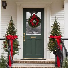 two christmas wreaths on the front steps of a house