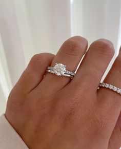 a woman's hand with two wedding rings on top of her finger and the ring is