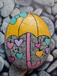 a painted rock with hearts holding an umbrella