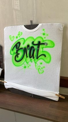 a white t - shirt with the word brit painted on it in green spray paint